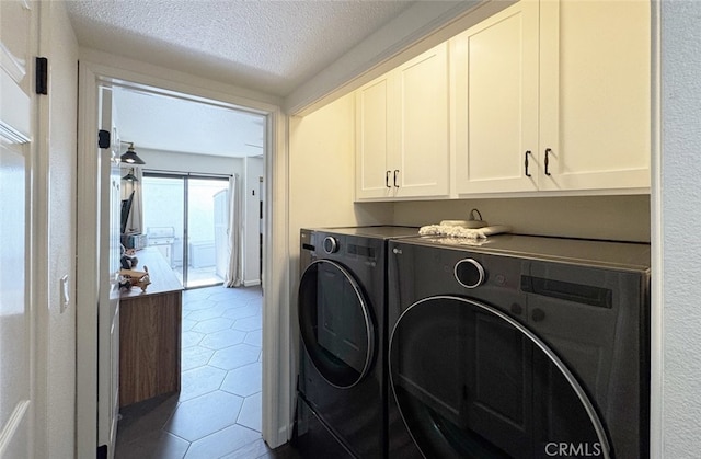 laundry room featuring a textured ceiling, separate washer and dryer, tile patterned flooring, and cabinet space