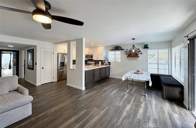 living room featuring a textured ceiling, dark wood finished floors, a ceiling fan, and baseboards