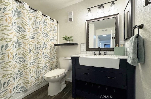 bathroom featuring toilet, visible vents, wood finished floors, and vanity