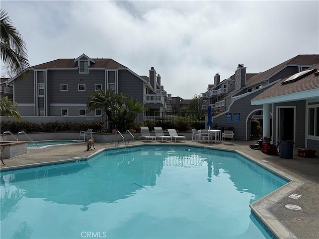 community pool featuring a residential view, a patio area, and fence