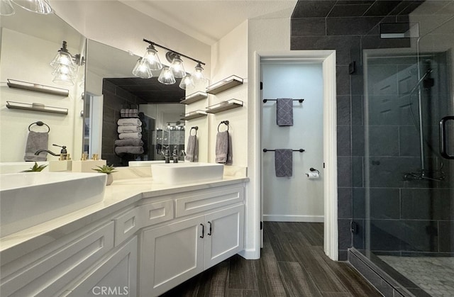 full bathroom with double vanity, a sink, a shower stall, and wood finished floors