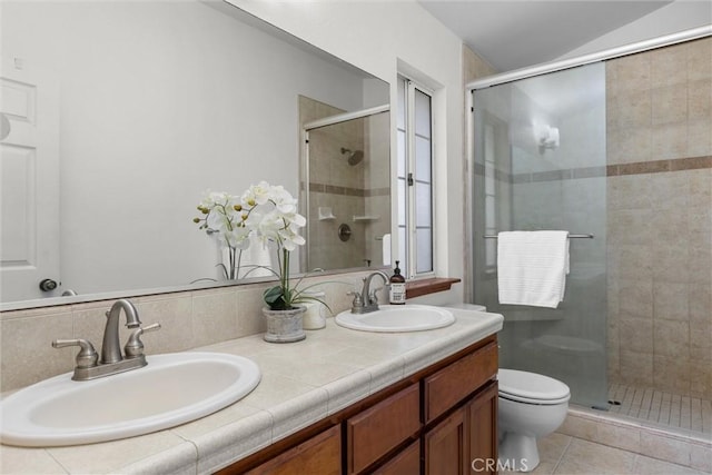 bathroom with double vanity, a sink, toilet, and a shower stall