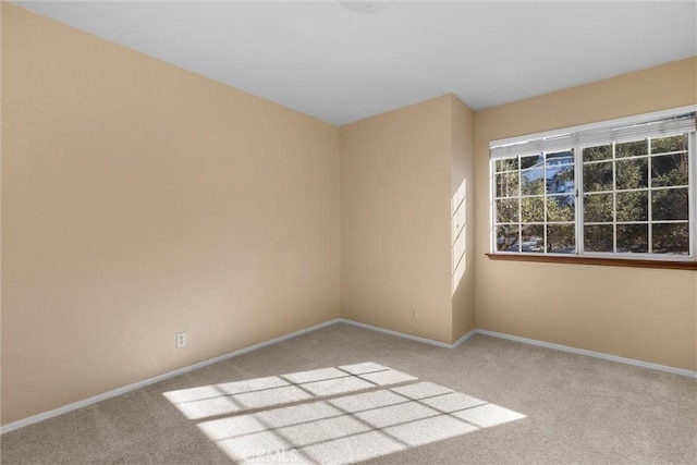 spare room featuring carpet floors and baseboards