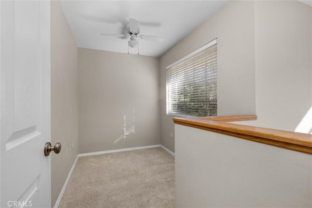 unfurnished room featuring light carpet, a ceiling fan, and baseboards