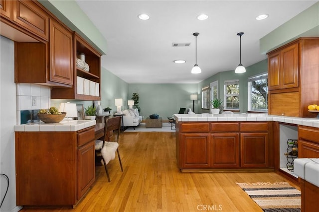 kitchen with brown cabinets, light wood-type flooring, and open floor plan