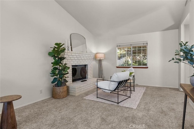 carpeted living area with vaulted ceiling, a brick fireplace, and baseboards