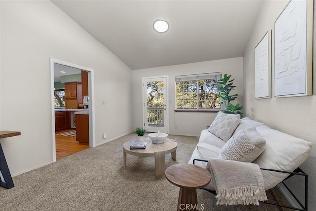 living area with lofted ceiling, baseboards, and light colored carpet