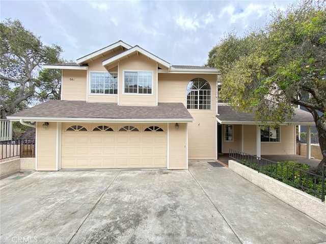 traditional home with an attached garage, a shingled roof, and driveway