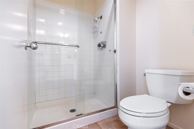 bathroom with toilet, a stall shower, and tile patterned flooring