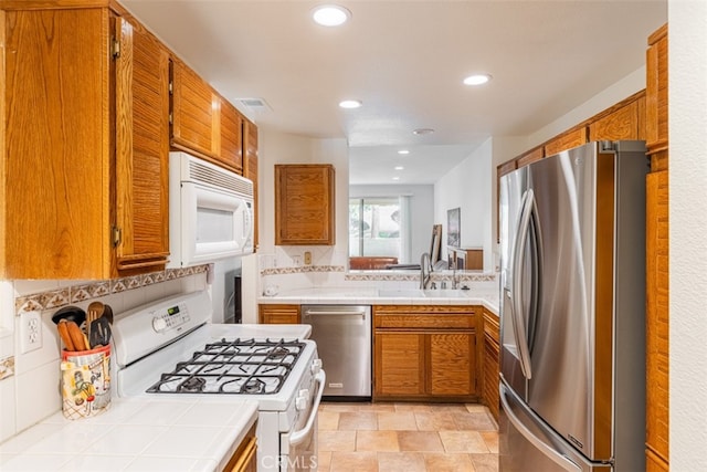 kitchen featuring brown cabinets, visible vents, stainless steel appliances, and a sink