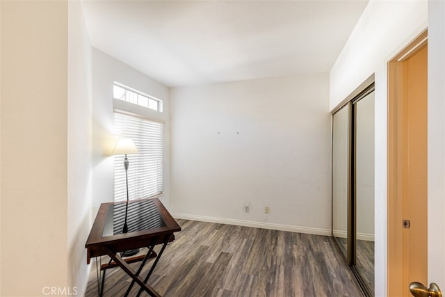 interior space featuring a closet, dark wood-style flooring, and baseboards