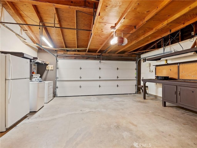 garage featuring a garage door opener, washing machine and clothes dryer, and freestanding refrigerator