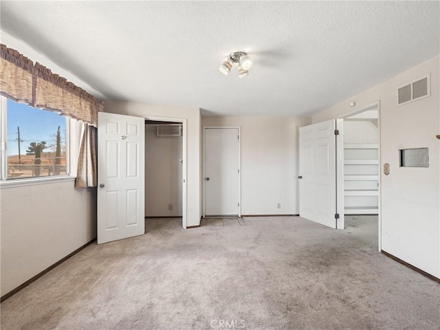 unfurnished bedroom with visible vents, light carpet, baseboards, and two closets