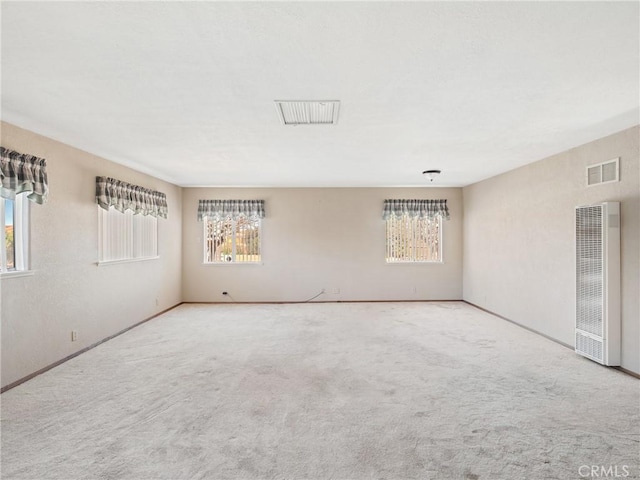 spare room with light carpet, a heating unit, and visible vents