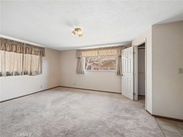 unfurnished bedroom featuring light carpet, baseboards, and a textured ceiling