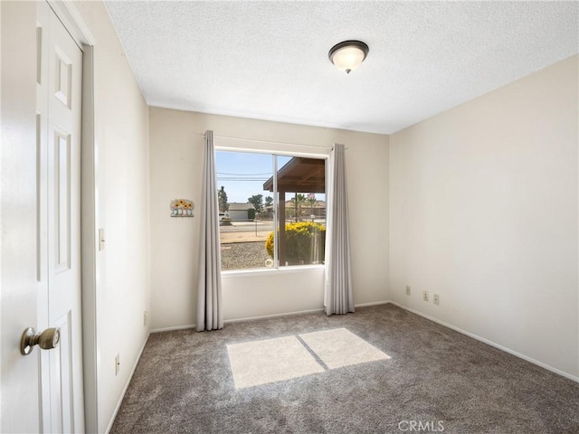 unfurnished room featuring a textured ceiling, baseboards, and carpet flooring