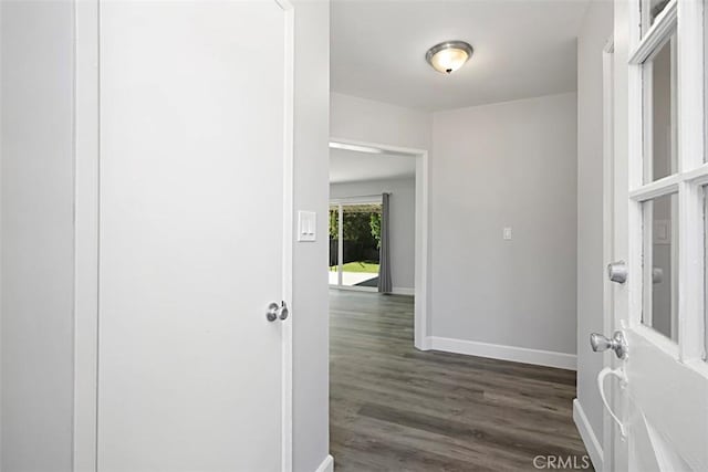 corridor featuring dark wood finished floors and baseboards