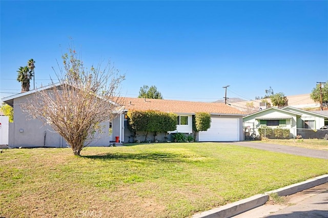 single story home featuring aphalt driveway, a garage, fence, stucco siding, and a front yard