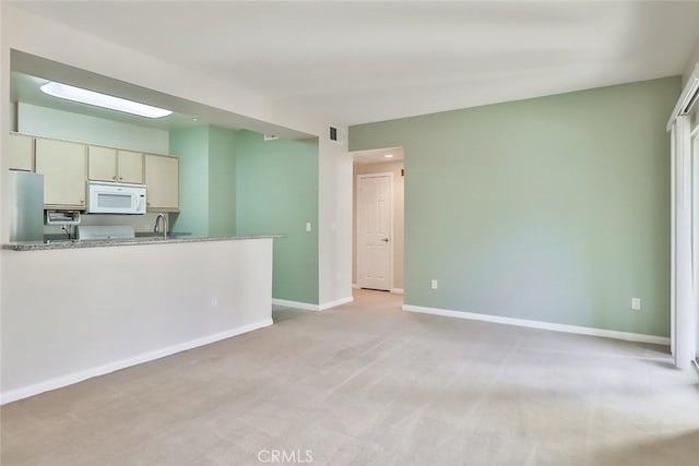 unfurnished living room with light carpet, a sink, visible vents, and baseboards