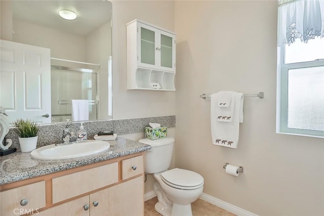 bathroom with toilet, a stall shower, vanity, and baseboards