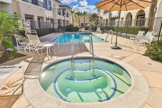 pool with a community hot tub, fence, a residential view, and a patio