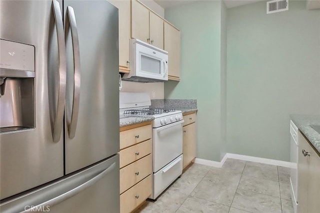 kitchen featuring light tile patterned floors, light countertops, visible vents, white appliances, and baseboards