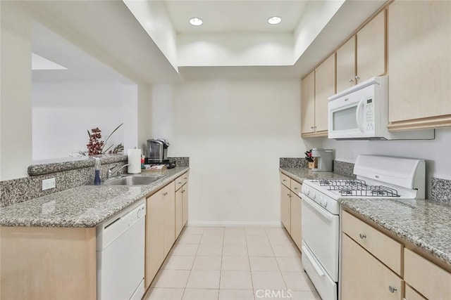 kitchen with white appliances, a sink, baseboards, light stone countertops, and a tray ceiling