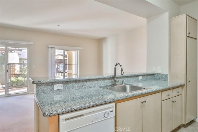 kitchen with a sink, a peninsula, light stone counters, and dishwasher