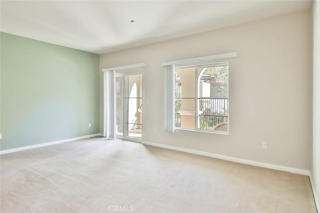 unfurnished room featuring light carpet and baseboards