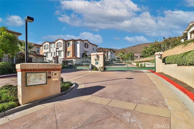 view of road with street lighting, a residential view, a gated entry, curbs, and a gate