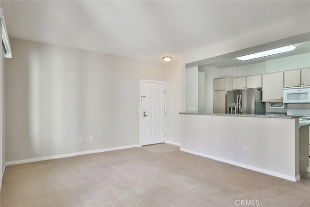 kitchen featuring a peninsula, white microwave, stone counters, and stainless steel fridge with ice dispenser