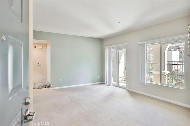 unfurnished room with baseboards and light colored carpet