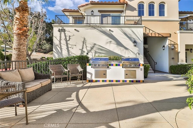 view of patio with a balcony, grilling area, and an outdoor kitchen