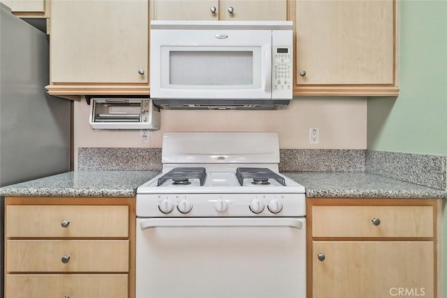 kitchen featuring light stone countertops, white appliances, and light brown cabinetry