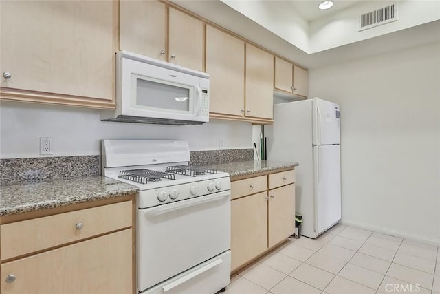 kitchen featuring light stone counters, white appliances, visible vents, and light brown cabinets