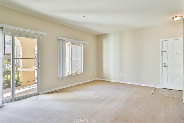 unfurnished room with light carpet and baseboards