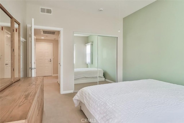 bedroom with light carpet, baseboards, visible vents, and a closet