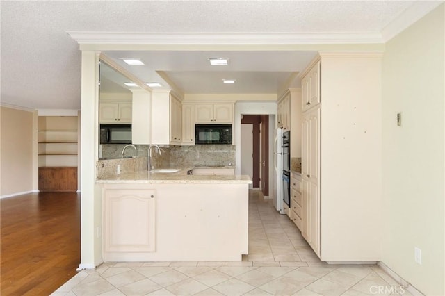 kitchen with a peninsula, a sink, crown molding, black microwave, and backsplash