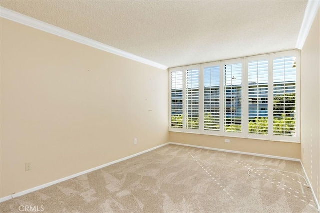 spare room featuring a textured ceiling, carpet floors, baseboards, and crown molding