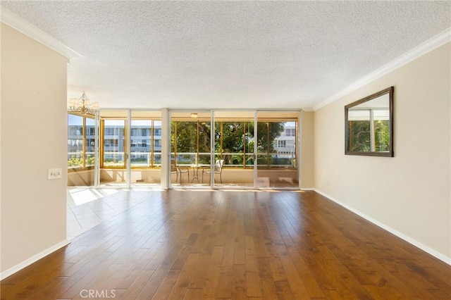 spare room with ornamental molding, a textured ceiling, baseboards, and hardwood / wood-style flooring