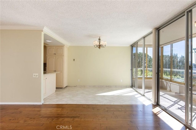 empty room featuring a wall of windows, light wood-type flooring, crown molding, and an inviting chandelier