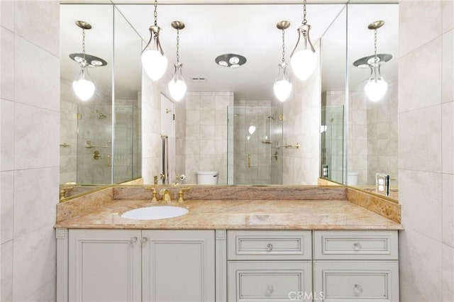 full bathroom featuring tile walls, visible vents, toilet, a stall shower, and vanity