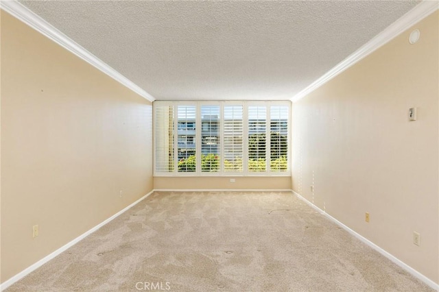 carpeted spare room with baseboards, ornamental molding, and a textured ceiling