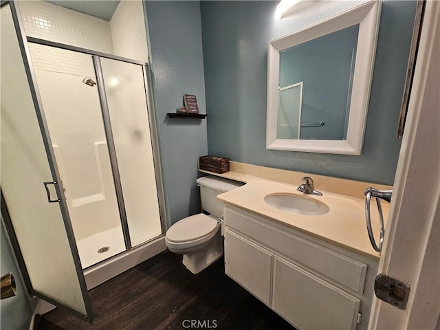 bathroom with toilet, wood finished floors, a shower stall, and vanity