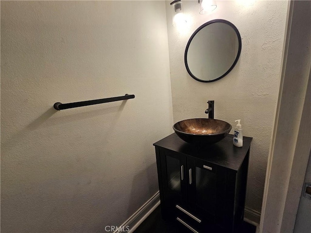 bathroom featuring a textured wall, vanity, and baseboards