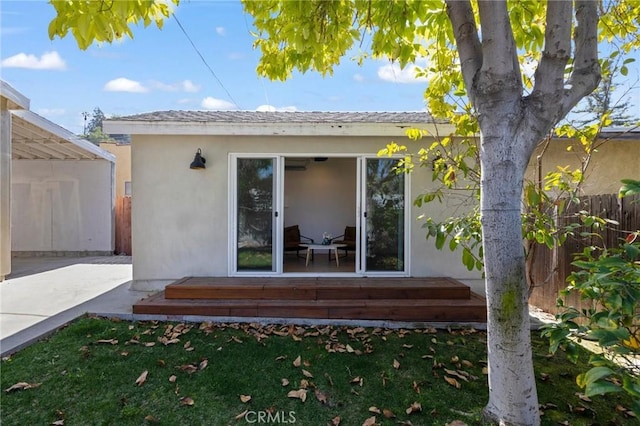 back of property featuring a yard, fence, and stucco siding