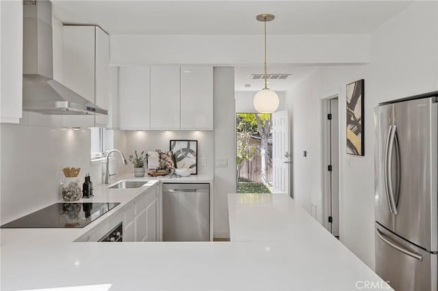 kitchen with stainless steel appliances, a sink, light countertops, wall chimney range hood, and modern cabinets