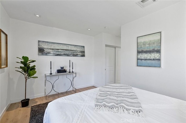 bedroom with recessed lighting, visible vents, baseboards, and wood finished floors