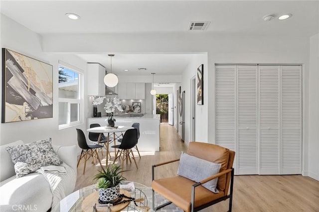 living area with a healthy amount of sunlight, light wood-style flooring, and visible vents