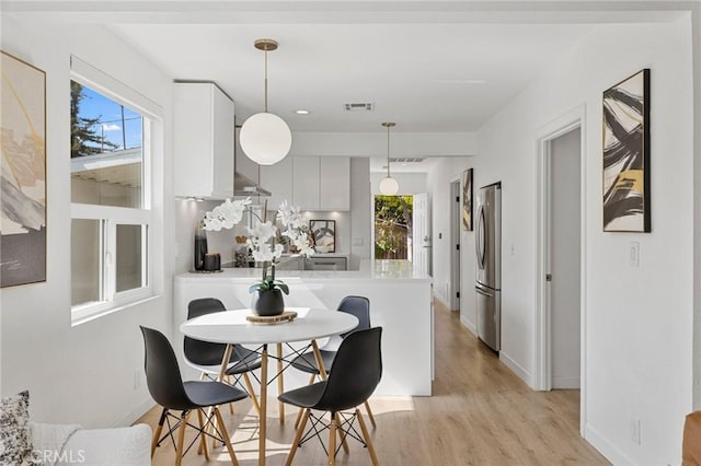 dining room featuring baseboards, light wood-type flooring, visible vents, and a healthy amount of sunlight